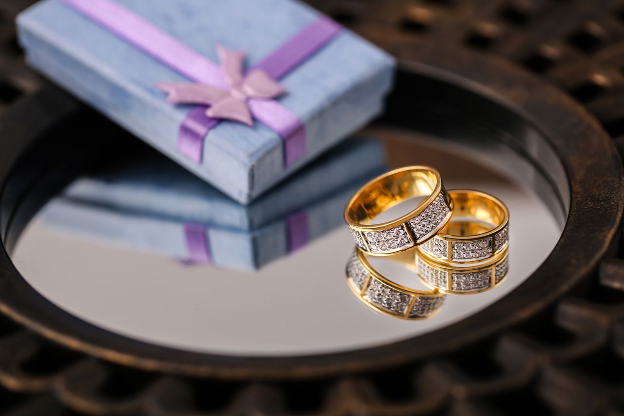 Close-up of gold wedding rings reflecting next to a blue gift box.